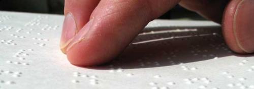 Fingers reading braille book.