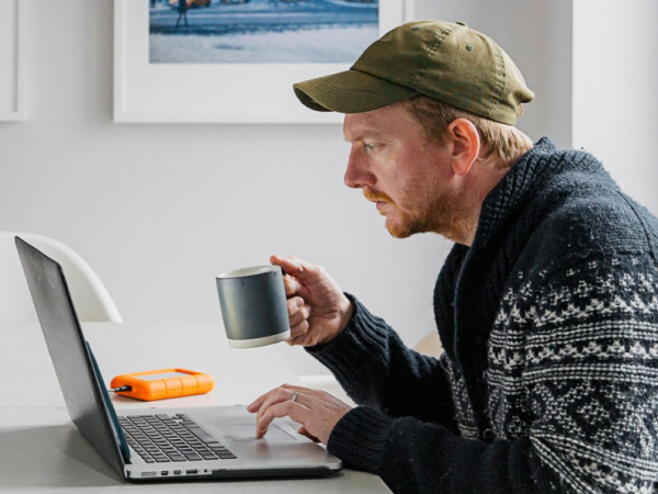 A person drinking coffee while checking the laptop